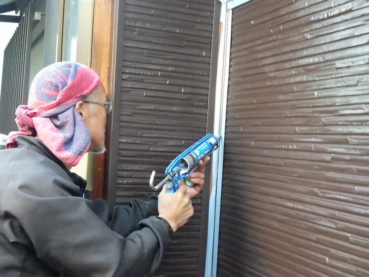 復旧した外壁と雨戸の取り合い部分にシーリング処理を行っている様子