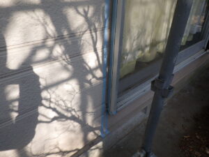 サッシのコーキングの線に合わせて、マスキングテープを貼り付けていきます。