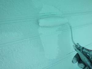 作業を平行して、外壁の上塗り塗装を進めて行きます。 下塗り・中塗りと違い、上塗りの塗料はかなり伸びます。 縦に塗料を配り、横で均していきます。