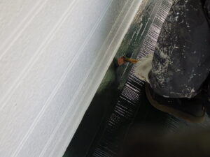 玄関屋根の上塗り塗装を行っていきます。 上塗り塗装を行うことで、塗装の最終工程として美観を整えて、紫外線や雨風から屋根材を保護して寿命を延ばします。 中塗りの塗りムラを無くし、塗膜に十分な厚みを持たせることで、長期間家を守る重要な作業になってきます。