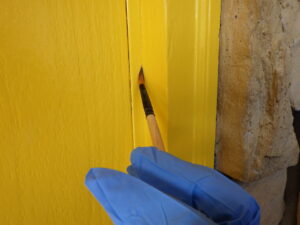 細かな補修を行っていきます。 玄関ドア枠の小さな隙間に筆で塗装をしていきます。 このひと手間を加えることで、とても仕上がりが綺麗に見えます。