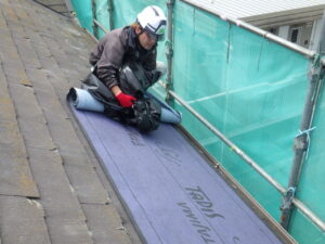 既存の屋根カバーの掃除を行い、ルーフィングを貼り付けていきます。 ルーフィングとは、瓦やスレートなどの屋根材の下に敷く「防水シート」の役割を持ちます。 ルーフィングが健全であれば、屋根材が多少破損していても雨漏りは防げます。