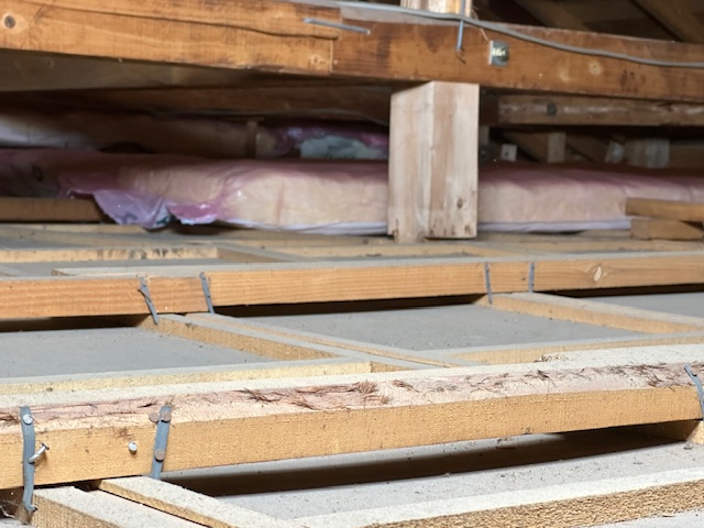 天井裏の奥側から断熱材を入れている様子