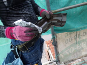 軒樋の取り付け作業に移ります。 コーナー継手に専用接着材を塗布し、軒樋にジョイントさせ、固定していきます。