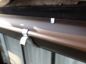 専用接着材で取り付けた後は、吊り金具で軒樋をしっかりと固定していきます。軒樋と吊り金具との間が空いてしまっていると、風の揺れで軒樋がたわんだりし、最悪の場合外れる危険性がある為、確認をしながら、固定を進めて行きました。