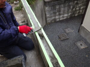 横筋ブロックの溝にモルタルを充填している様子になります。 この部分に充填するのは、見た目だけではなく、構造的にかなり重要になります。 モルタルを充填することでブロック同士が一体構造となり、地震や外力によるひび割れ・ズレを抑えて、強度を上げれます。