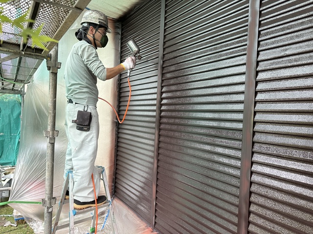 雨戸の上塗りを吹付けで施工している様子